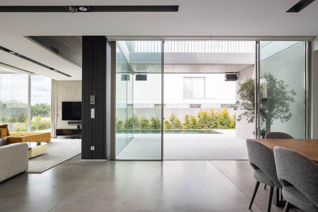 Contemporary living and dining area with large sliding glass doors opening to a patio and pool, blending indoor and outdoor spaces with minimalist design.
